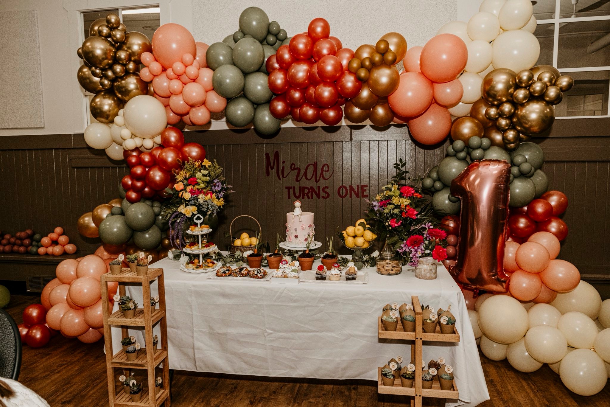 First birthday dessert table framed by a sculptural balloon installation