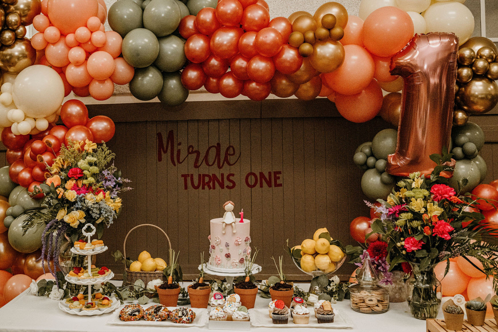 Floral first birthday dessert table with balloon arch